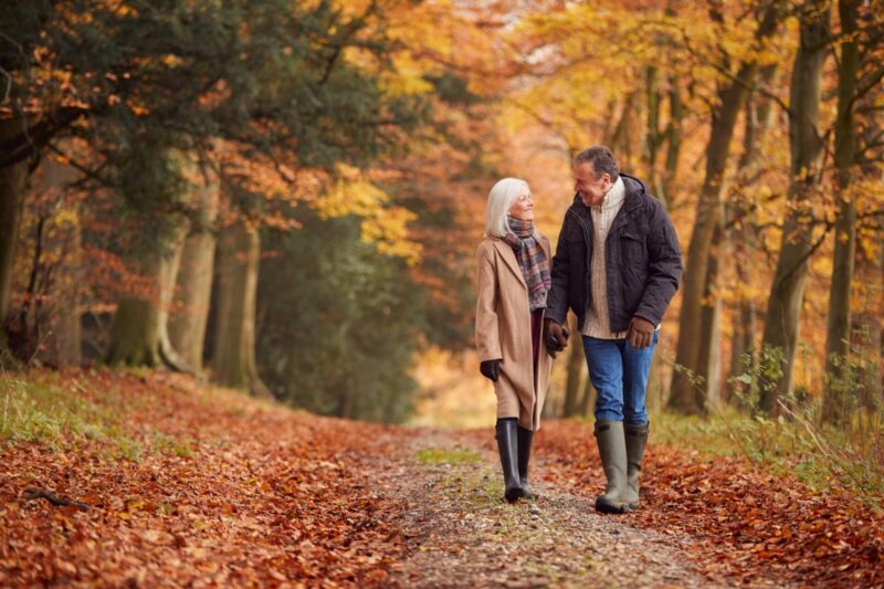 An older couple walking through woodland.