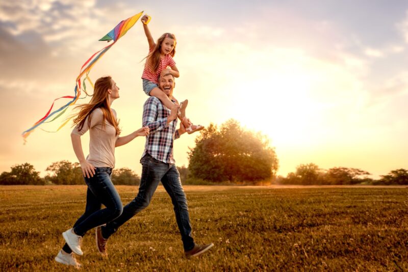 A family in a field running with a kite