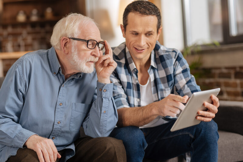 Young man showing his elderly father something on a tablet