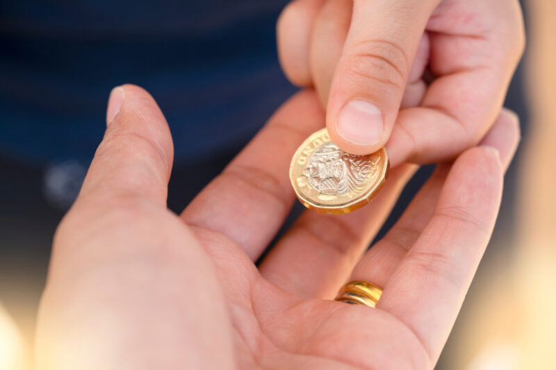 Someone passing a £1 coin to another person.