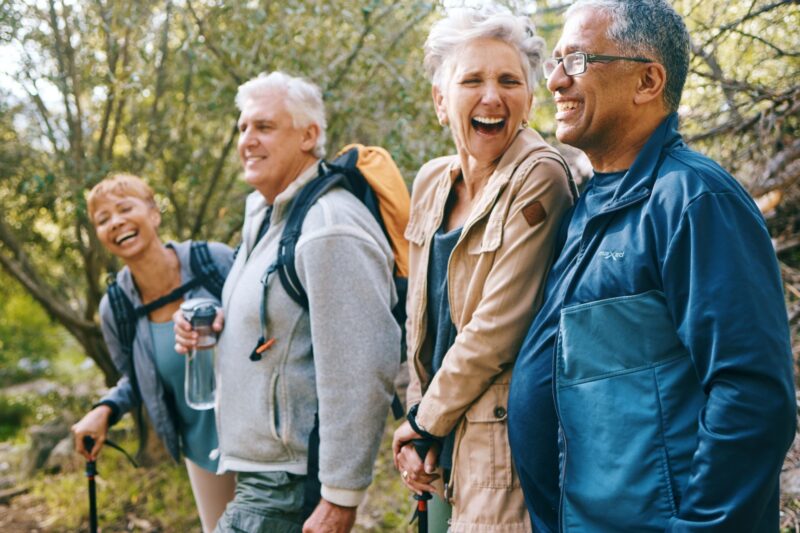 Four older people laughing and hiking together